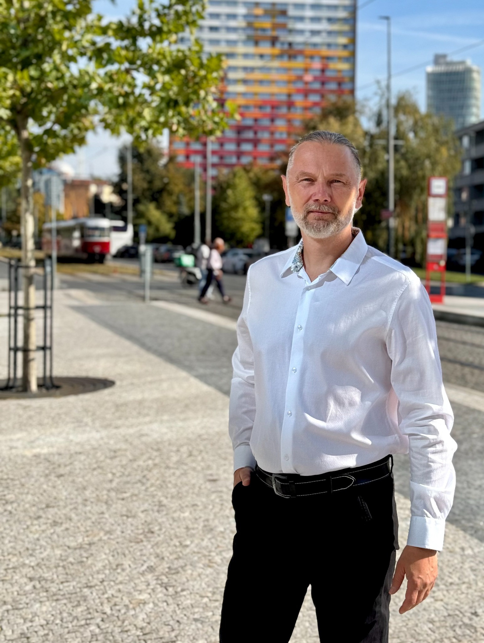 Roman Faltýn v bílé košili před domy na Invalidovně
